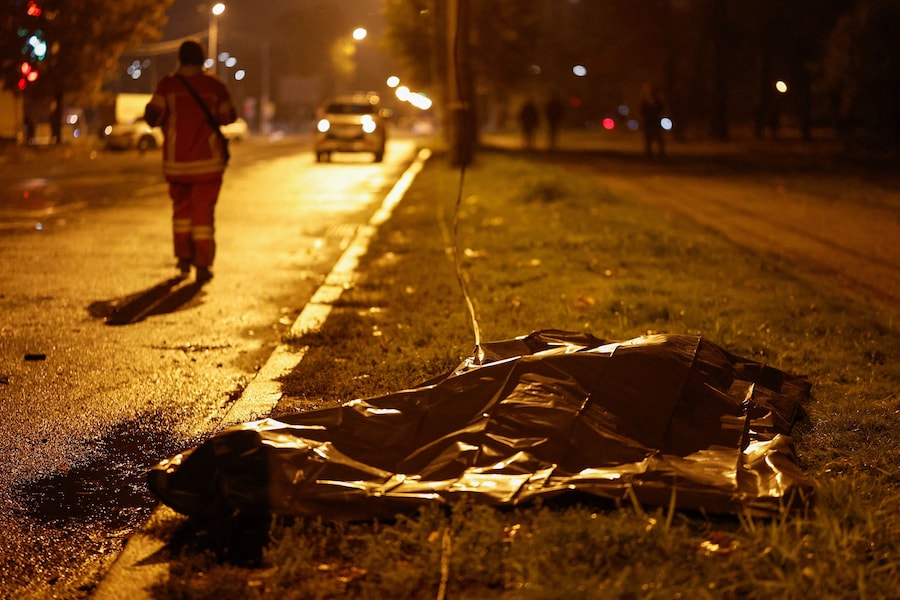 Un soccorritore cammina accanto al corpo di un abitante ucciso in strada da un attacco missilistico russo, nel contesto dell'offensiva russa contro l'Ucraina, a Kiev. (REUTERS)