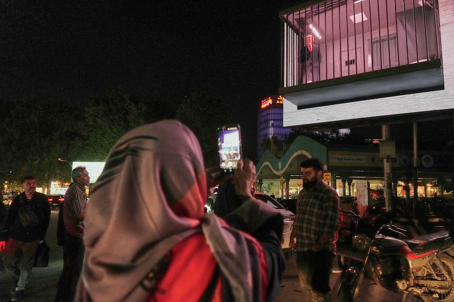 In piazza Tajrish a Teheran, in Iran, alcune persone osservano un cartellone pubblicitario che raffigura un attore nei panni del presidente degli Stati Uniti Donald Trump dietro le sbarre in una finta cella di prigione (APN)