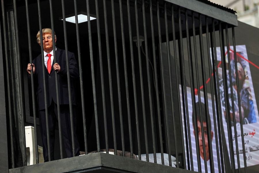 Una persona travestita da presidente degli Stati Uniti Donald Trump si trova all’interno di una cella carceraria simulata durante uno spettacolo a Teheran, in Iran (via REUTERS)