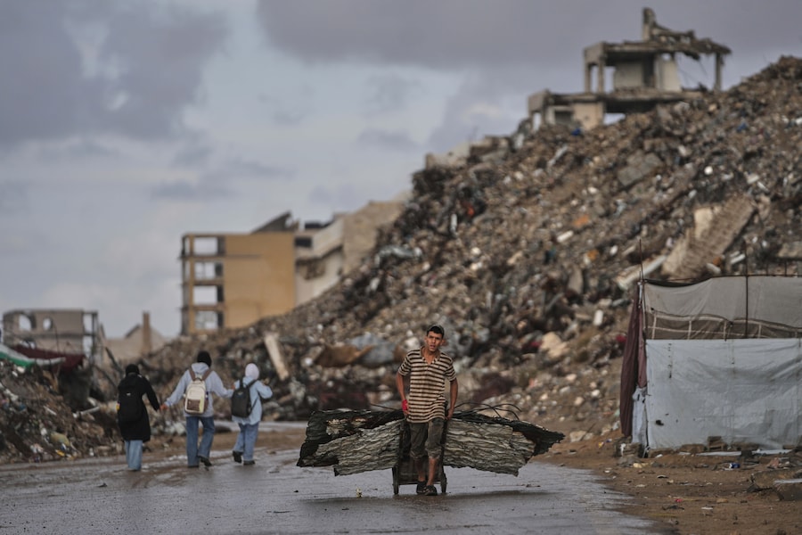 Un uomo palestinese trasporta lamiere metalliche tra le rovine degli edifici distrutti durante la guerra tra Israele e Hamas nella città di Gaza (APN)