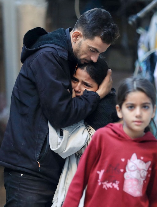 Un uomo palestinese consola una bambina sconvolta dalle conseguenze di un attacco israeliano contro un appartamento, nella città di Gaza (REUTERS)