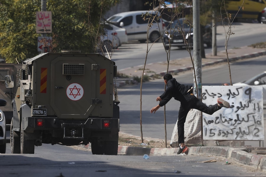 Un ragazzo palestinese lancia pietre contro le truppe israeliane durante un raid dell’esercito israeliano nel campo profughi di Balata, vicino alla città di Nablus in Cisgiordania (EPA)