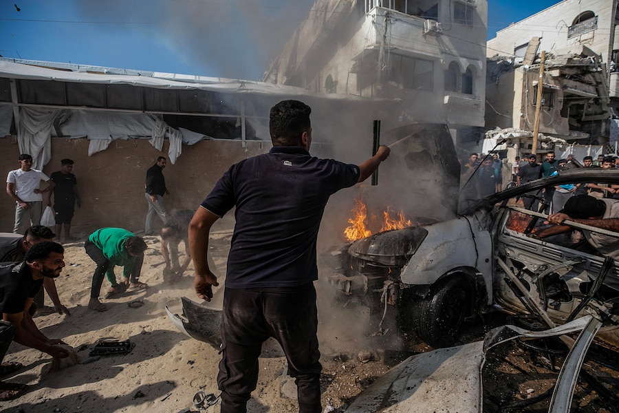 Alcuni palestinesi tentano di spegnere un incendio in un veicolo distrutto da un attacco aereo israeliano a sud di Gaza City (EPA)