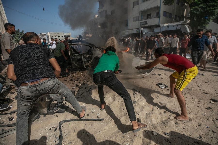 Alcuni palestinesi tentano di spegnere un incendio in un veicolo distrutto da un attacco aereo israeliano a sud della città di Gaza (EPA)
