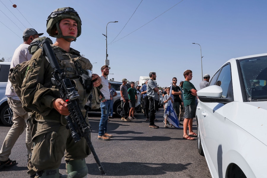 Un membro delle forze armate israeliane sorveglia la zona mentre i coloni israeliani si radunano in seguito a una sparatoria avvenuta a Hebron, nella Cisgiordania occupata da Israele, il 23 ottobre 2026. (REUTERS)