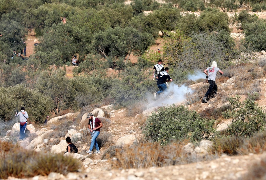 Gli attivisti che aiutano gli agricoltori palestinesi nella raccolta delle olive vengono dispersi dalle forze israeliane con i gas lacrimogeni, nei pressi dell’insediamento ebraico di Ma’on, in Cisgiordania, a sud di Hebron, il 22 ottobre 2022. Attivisti internazionali per la pace hanno aiutato i palestinesi nella raccolta delle olive, mentre soldati israeliani e agenti della Polizia di Frontiera erano nelle vicinanze per assicurarsi che non si verificassero scontri tra i palestinesi e i coloni ebrei. (EPA)