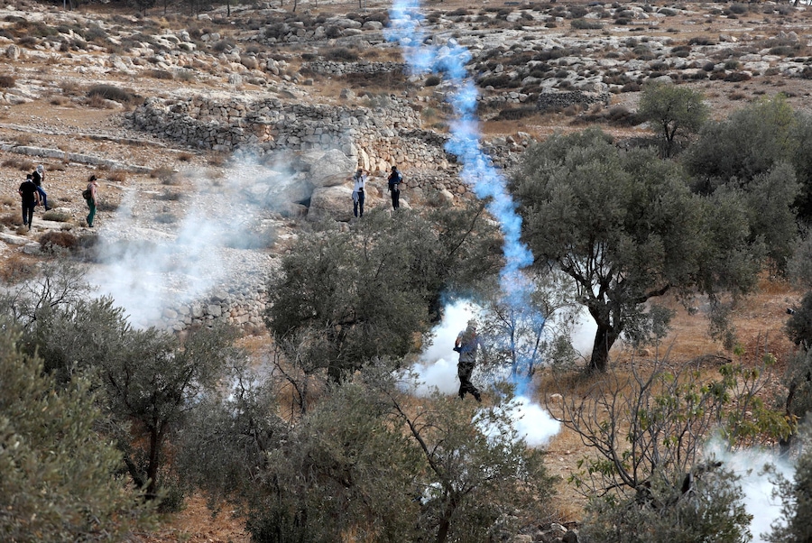 Gli attivisti che aiutano gli agricoltori palestinesi nella raccolta delle olive vengono dispersi dalle forze israeliane con i gas lacrimogeni, nei pressi dell’insediamento ebraico di Ma’on, in Cisgiordania, a sud di Hebron, il 22 ottobre 2022. Attivisti internazionali per la pace hanno aiutato i palestinesi nella raccolta delle olive, mentre soldati israeliani e agenti della Polizia di Frontiera erano nelle vicinanze per assicurarsi che non si verificassero scontri tra i palestinesi e i coloni ebrei. (EPA)