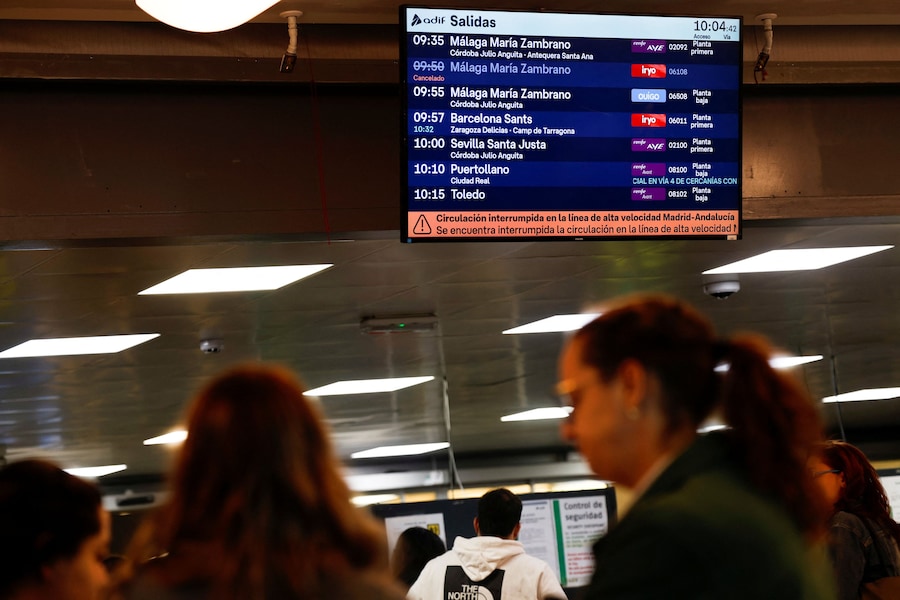 Alla stazione ferroviaria di Atocha a Madrid, in Spagna, il 28 ottobre 2026, alcune persone passano sotto uno schermo informativo che mostra un messaggio in cui si comunica che la linea ferroviaria ad alta velocità tra Madrid e l’Andalusia è stata interrotta a seguito della collisione tra due treni ad alta velocità avvenuta tra le località di Mora e Orgaz. (REUTERS)