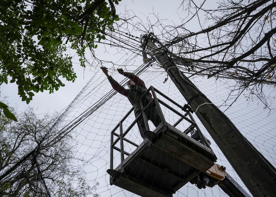 Un operaio installa delle reti anti-drone sopra una strada nella città di Kherson. (REUTERS)