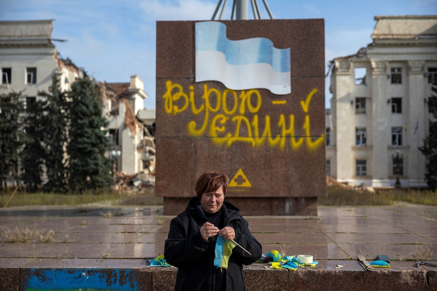 Olha Chiupikova, dipendente comunale, espone bandiere ucraine in onore dei militari caduti durante una tregua regionale, nel contesto dell’attacco russo all’Ucraina, a Kherson. (REUTERS)
