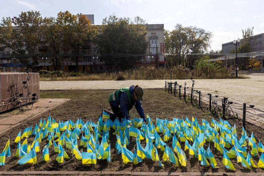 Un dipendente comunale espone bandiere ucraine in onore dei militari caduti durante una tregua regionale, nel contesto dell'attacco russo all'Ucraina, a Kherson, Ucraina. (REUTERS)