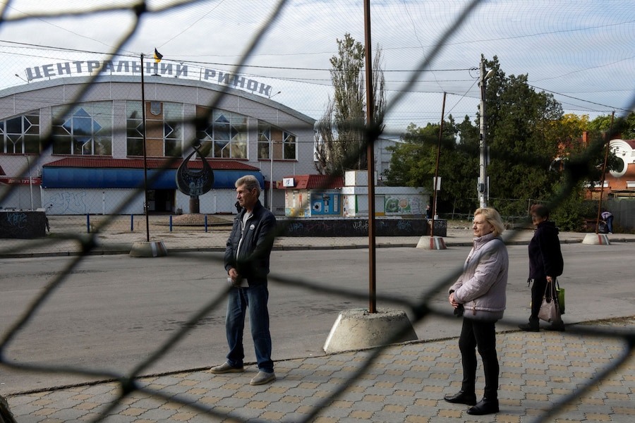 Alcune persone attendono alla fermata dell'autobus in una strada coperta da reti anti-drone durante una tregua regionale, nel contesto dell'attacco della Russia all'Ucraina, a Kherson. (REUTERS)