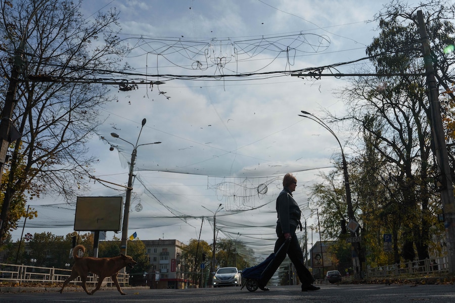 Una donna cammina sotto le reti anti-drone tese sopra una strada durante una tregua locale legata a una missione di aiuti umanitari a Oleshky, nella regione di Kherson, in Ucraina. (APN)