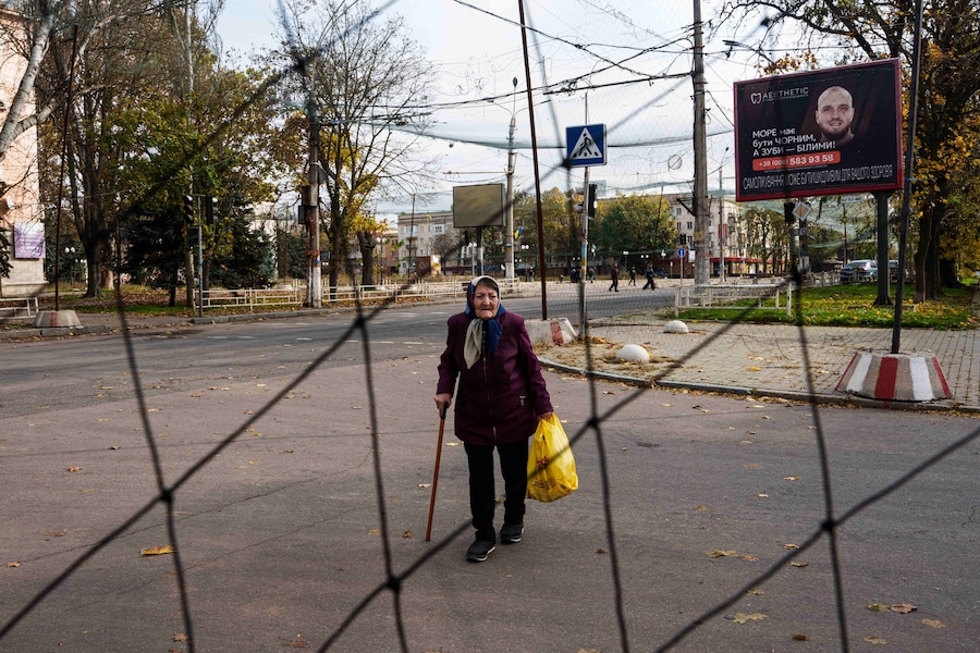 Una donna anziana cammina sotto le reti anti-drone tese sopra una strada durante una tregua locale legata a una missione di aiuti umanitari a Oleshky, nella regione di Kherson, in Ucraina. (APN)