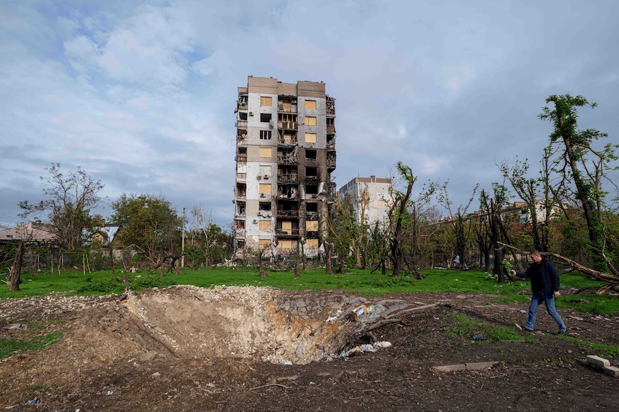 Un uomo scatta delle foto a un cratere e ad alcune abitazioni danneggiate dai bombardamenti russi durante una tregua locale legata a una missione di aiuti umanitari a Oleshky, nella regione di Kherson, in Ucraina. (APN)