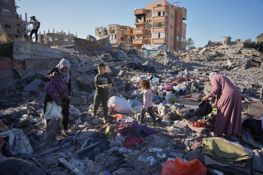 Alcuni palestinesi setacciano le macerie di un edificio distrutto durante un attacco israeliano sferrato nella notte nel campo profughi di Bureij, nella parte centrale della Striscia di Gaza. (AP Photo/Abdel Kareem Hana/APN)
