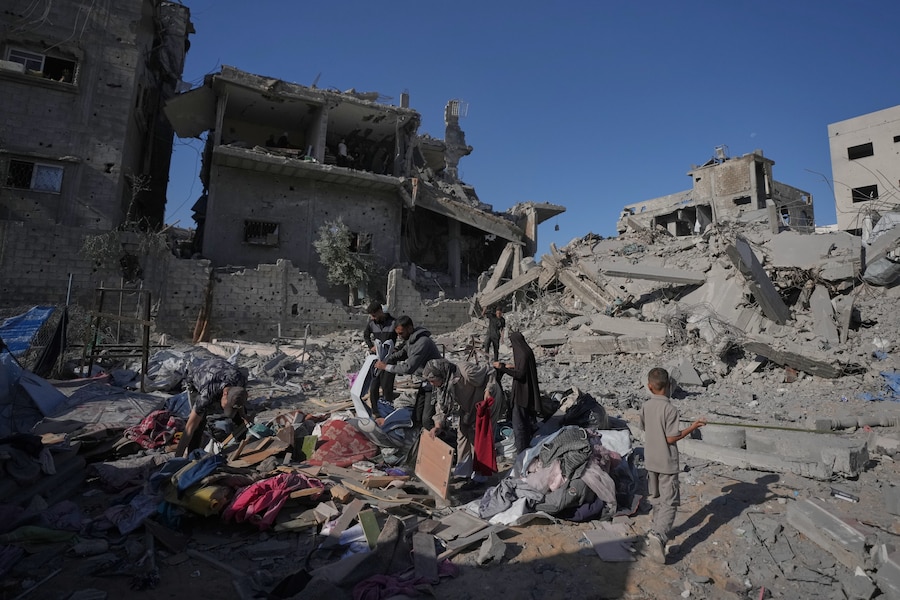 Alcuni palestinesi recuperano i propri effetti personali tra le macerie di un'abitazione distrutta da un attacco dell'esercito israeliano a nord della città di Gaza. (AP Photo/Jehad Alshrafi/APN)