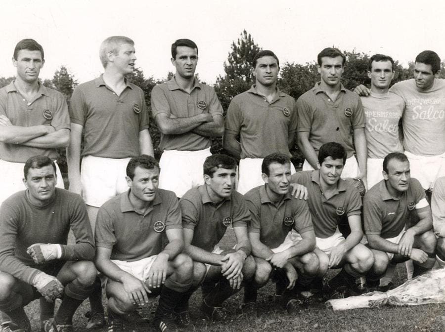 1964, Stadio comunale  di Abbadia San Salvatore (Siena), Campionato 1964-65, la squadra As Roma in ritiro estivo: in piedi (da sin.) Fulvio Francesconi (A), il tedesco Karl Heinz Schnellinger (C), Francesco Carpenetti (D), Lamberto Leonardi (A), l'argentino Antonio Valentin Angelillo (A); accosciati (da sin.) Enzo Matteucci (P), Giuseppe Tamborini (C), Mario Ardizzon (D), Glauco Tomasin (D), Giancarlo De Sisti (C), Giacomo Losi (D). All'estrema destra, con maglia più chiara, i calciatori di una squadra locale (Ansa)