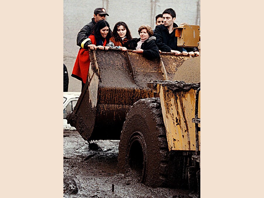 Con le lacrime agli occhi alcune donne vengono portate via con una pala meccanica dalla loro casa invasa dal fango venuto giu' in gran quantita' dalla vicina montagna. (Ciro Fusco)