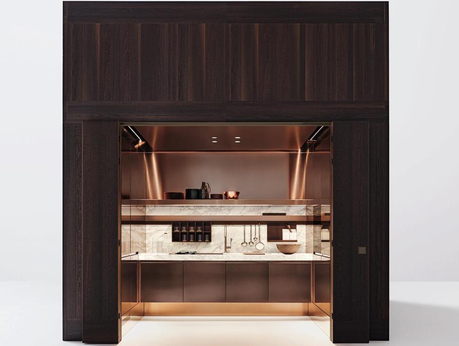 Arclinea, design Antonio Citterio. La cucina Convivium con ante con finitura in PVD bronzo è celata dal modulo Closet con ante Modus con apertura orizzontale a pacchetto