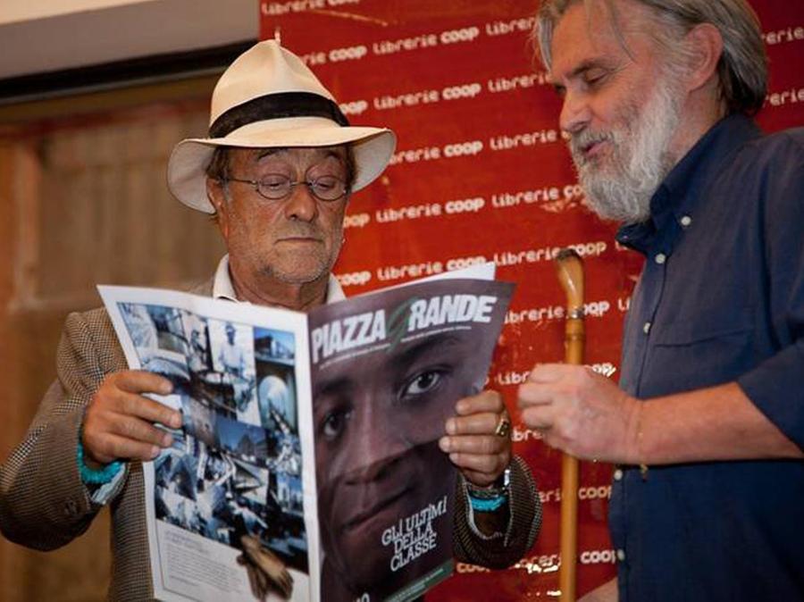 Lucio Dalla guarda il giornale di “Piazza grande” insieme a Roberto Morgantini (Ansa)