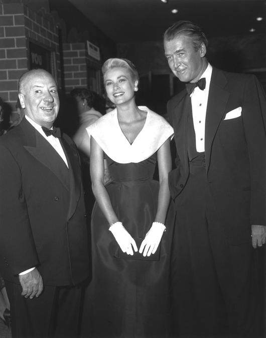 Grace Kelly con Alfred Hitchcock e James Stewart alla premiere di “La finestra sul cortile” nel 1954. Indossa l'abito Caracas, della collezione Christian Dior-New York, primavera-estate 1954 (The Kobal Collection/Aurimages)