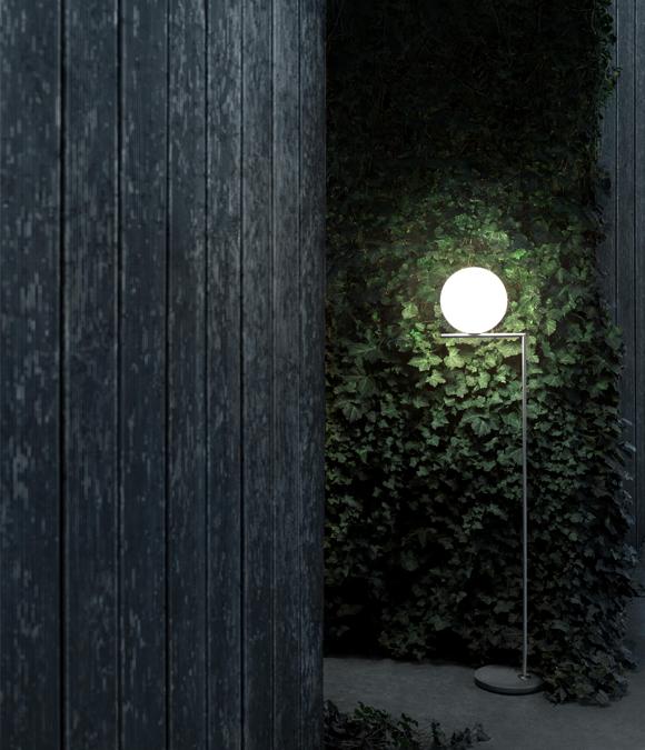 Flos, IC Outdoor, design Michael Anastassiades. Uno stelo di ottone satinato, combinato con raffinati materiali per la base: tre tipi di pietra lavica e un marmo travertino imperiale. In cima, come fosse in equilibrio, una sfera in vetro che sporge in bilico, sulla terminazione inclinata del bastone 
