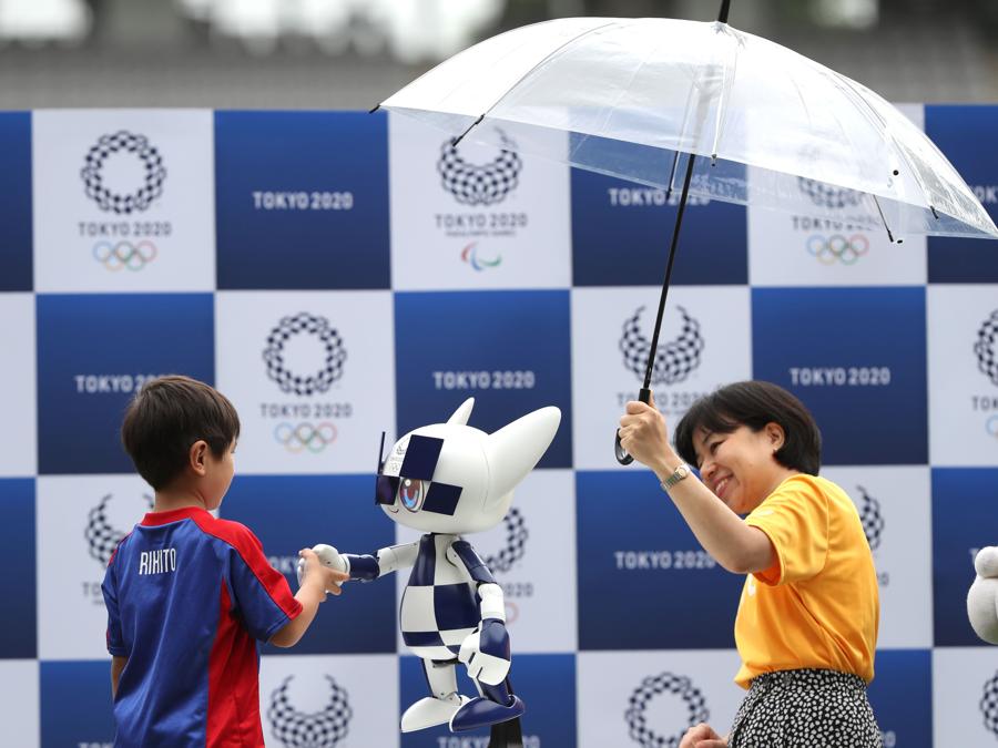 Un ragazzo stringe la mano al robot-mascotte  Miraitowa (Photo by Behrouz MEHRI / AFP)
