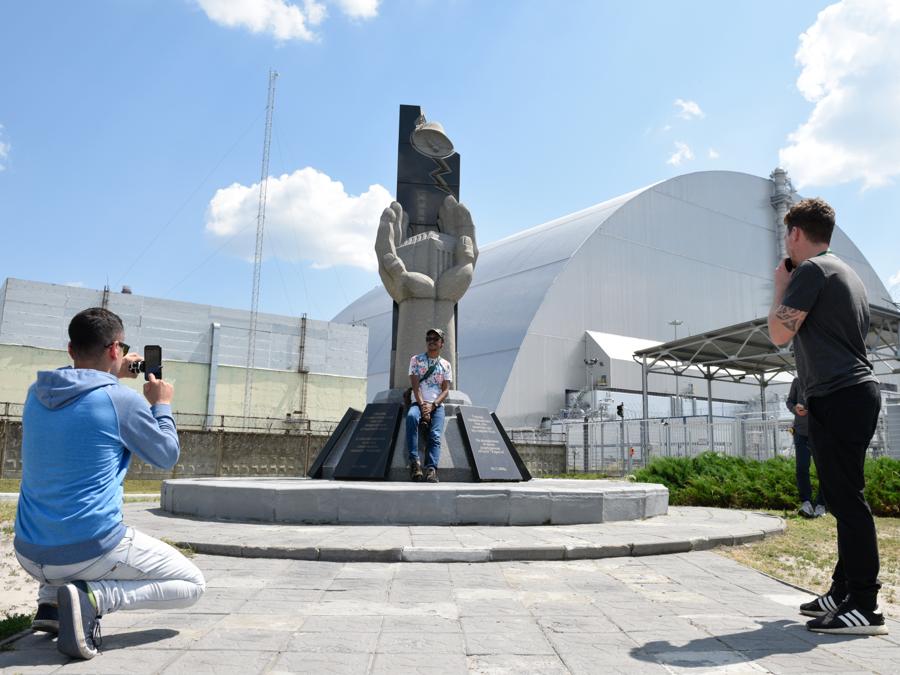 Turisti fotografano il monumento eretto in memoria delle vittime del disastro nucleare a Chernobyl  (Stringer / Sputnik)