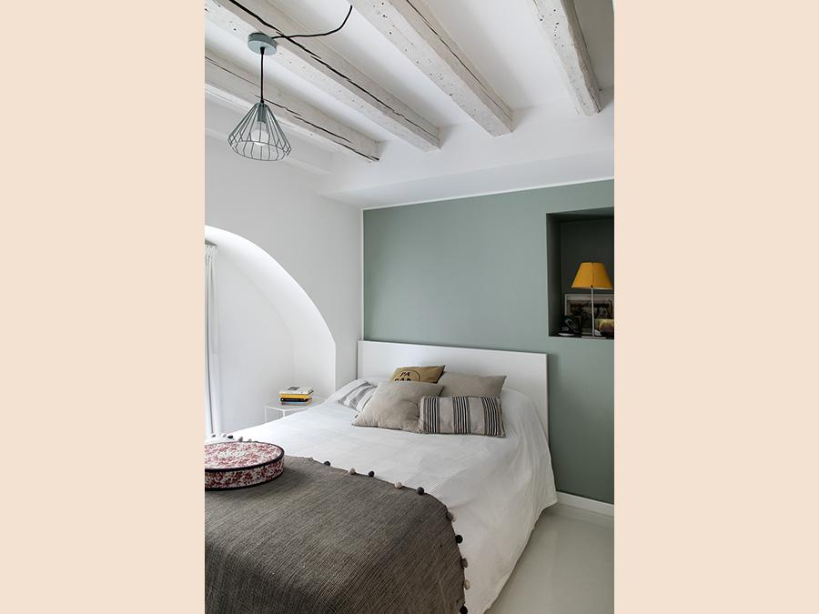Casa privata, progetto Clara Bona, Studio 98. Nella zona letto, con letto accostato a una parete per motivi di spazio, l'elemento decor è affidato a un'unica parete dipinta color salvia. Una nicchia fa la funzione di comodino (Giulio Oriani)