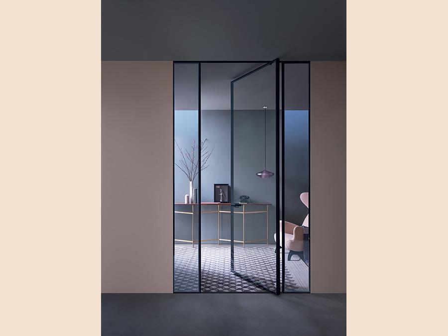Lualdi, Shoin Pivot. Porta a bilico in vetro trasparente con profilo bronzo. La presenza leggera di Shoin pivotante crea ambienti nitidi e accoglienti. Shoin Pivot è studiata per essere integrabile con pannelli apribili e fissi e si distingue per grande purezza formale