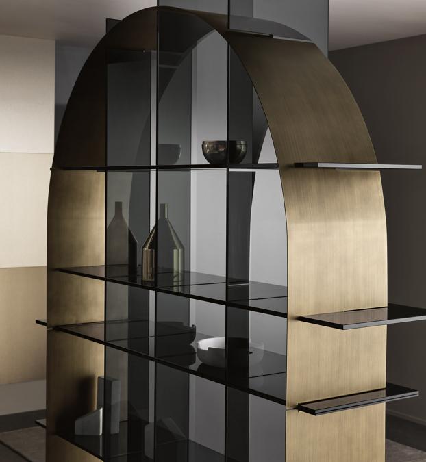 Paradigma di De Bona / De Meo per Tonelli Design. Libreria freestanding composta da una griglia centrale realizzata in vetro e da una componente geometrica ad incastro in lamiera sottile disponibile nella forma di arco o cerchio, con finitura a contrasto in bronzo spazzolato o nella nuova versione nero spazzolato. Il vetro può essere extrachiaro o fumè