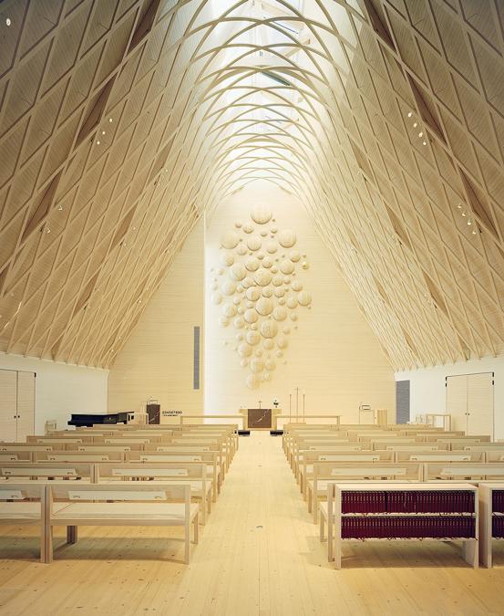 La tradizione del legno. Dalla forma archetipica di una capanna, la chiesa realizzata dallo studio OOPEAA in Finlandia, nella regione di Jyväskylä, è rivestita in piastrelle di ardesia ed è decorata da dettagli in legno e rame che sottolineano il contorno e le linee dell'edificio. All'interno, l'abete rosso locale rende l'ambiente caldo e confortevole e si unisce al frassino scelto per gli arredi e al tiglio dell'altare. Il soffitto in legno è caratterizzato da un guscio esterno e da una struttura a vista lamellare che percorre l'intera superficie. (Foto JUSSI TIAINEN) www.oopeaa.com