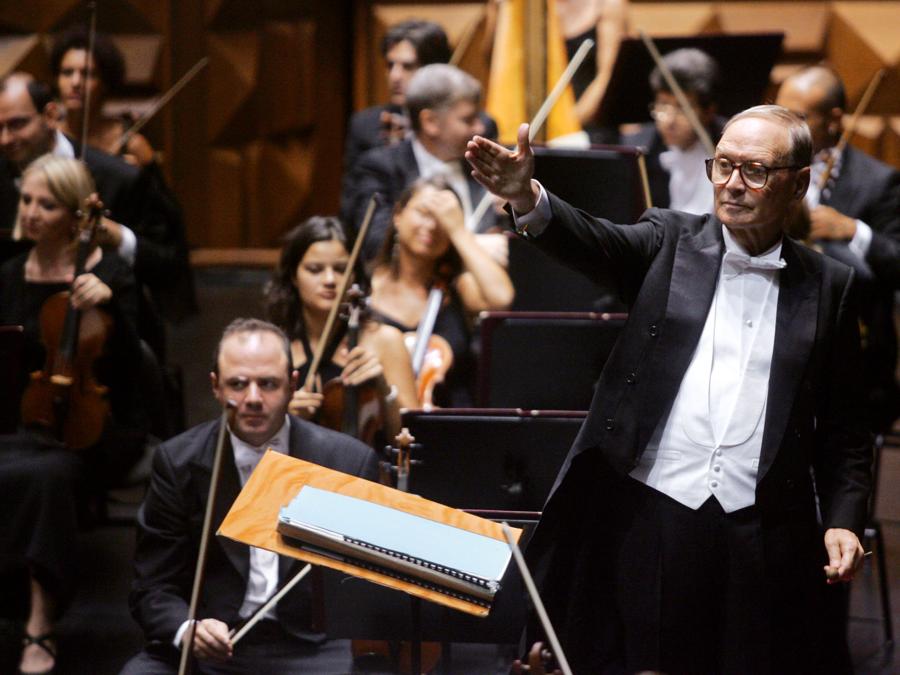 Ennio Morricone dirige la sua orchestra (Photo by GIULIO NAPOLITANO / AFP)