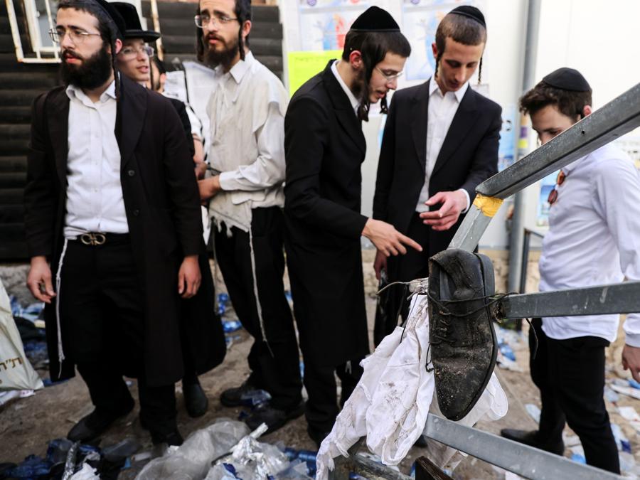 Gli ebrei ultraortodossi si trovano accanto agli averi rimasti sul Monte Meron, nel nord di Israele, dove sono stati segnalati incidenti mortali tra le migliaia di ebrei ultraortodossi riuniti presso la tomba di un saggio del II secolo per commemorazioni annuali che includono la preghiera e la danza per tutta la notte. (REUTERS/ Ronen Zvulun)