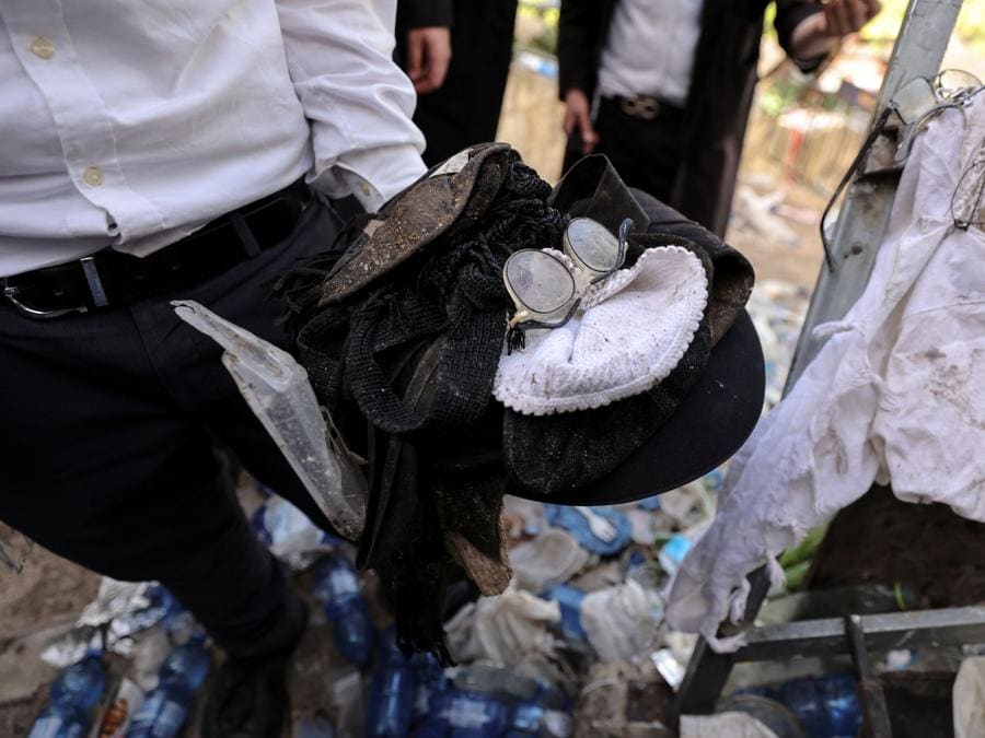 Un uomo detiene effetti personali di ebrei ortodossi sul monte Meron, nel nord di Israele, dove sono stati segnalati incidenti mortali tra le migliaia di ebrei ultraortodossi riuniti presso la tomba di un saggio del II secolo per commemorazioni annuali che includono la preghiera e la danza per tutta la notte. (REUTERS/ Ronen Zvulun)