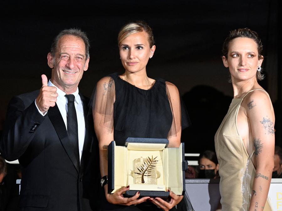 La regista francese Julia Ducournau posa affiancata dall’attore francese Vincent Lindon (a sinistra) e dall’attrice francese Agathe Rousselle dopo aver vinto la Palma d’oro per il film “Titane” durante la cerimonia di chiusura della 74a edizione del Cannes Film Festival. (Photo by John MACDOUGALL / AFP)