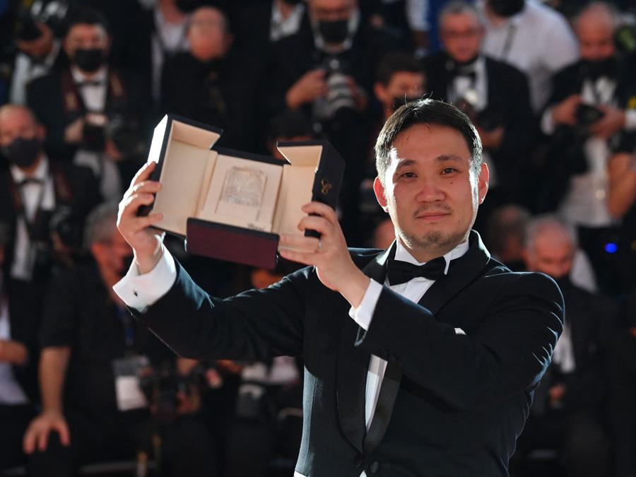 Il regista giapponese Ryusuke Hamaguchi posa dopo aver vinto il premio per la migliore sceneggiatura per il film “Drive My Car”, durante la cerimonia di chiusura della 74a edizione del Festival di Cannes. (Photo by CHRISTOPHE SIMON / AFP)