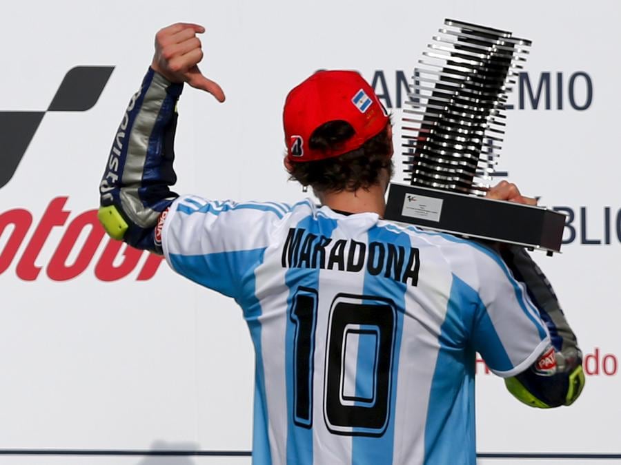 Valentino Rossi alza il trofeo mentre mostra la maglia di Diego Maradona sul podio dopo aver vinto il Gran Premio della MotoGP in Argentina sul circuito internazionale di Termas de Rio Hondo a Termas de Rio Hondo, 19 aprile 2015 (REUTERS/Marcos Brindicci)