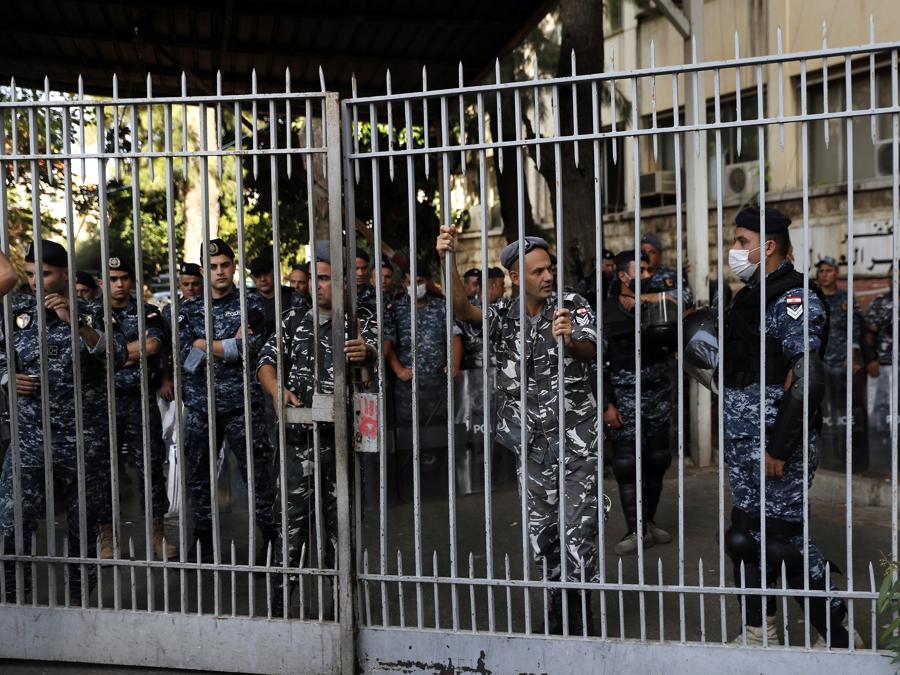 I poliziotti fanno la guardia all’interno del Palazzo di Giustizia mentre i sostenitori dei gruppi sciiti Hezbollah e Amal protestano contro il giudice Tarek Bitar che sta indagando sull’esplosione mortale del porto marittimo dello scorso anno, a Beirut, in Libano (AP Photo/Hussein Malla)