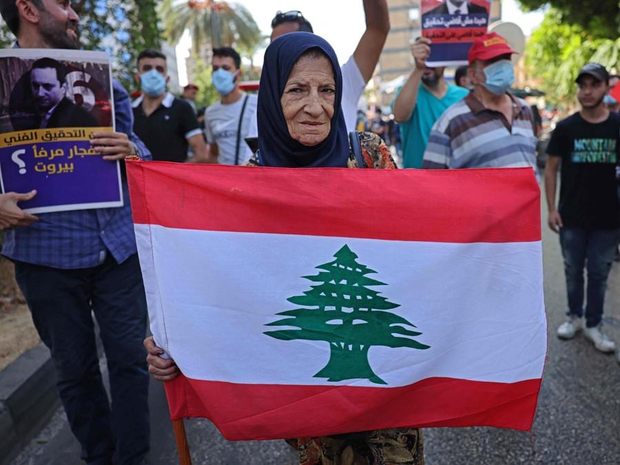 Una sostenitrice di Hezbollah e del movimento Amal sventola la bandiera nazionale vicino al Palazzo di Giustizia nella capitale Beirut il 14 ottobre 2021, durante una riunione per chiedere il licenziamento dell’investigatore capo dell’esplosione di Beirut. (Photo by JOSEPH EID / AFP)