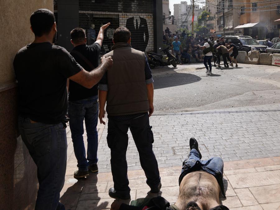sostenitori di un gruppo sciita alleato di Hezbollah chiedono aiuto per un compagno ferito durante gli scontri armati scoppiati durante una protesta nel sobborgo meridionale di Beirut di Dahiyeh, in Libano, giovedì 14 ottobre 2021. Non è stato immediatamente chiaro cosa abbia innescato la sparatoria , ma le tensioni erano alte lungo un’ex prima linea di guerra civile tra aree musulmane sciite e cristiane. (AP Photo/Hassan Ammar)