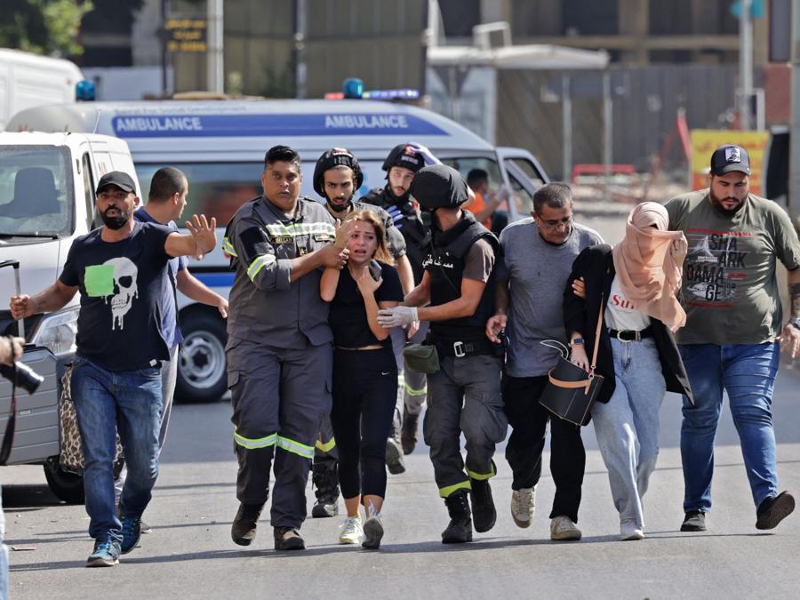 Medici libanesi aiutano a evacuare i civili durante gli scontri nella zona di Tayouneh, nel sobborgo meridionale della capitale Beirut, il 14 ottobre 2021, a seguito di una manifestazione dei sostenitori di Hezbollah e del movimento Amal. - Gli spari hanno ucciso almeno tre persone e ne hanno ferite 20 durante una manifestazione a Beirut organizzata dai movimenti sciiti Hezbollah e Amal per chiedere il licenziamento dell’investigatore capo dell’esplosione di Beirut. (Photo by JOSEPH EID / AFP)