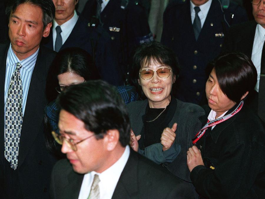Fusako Shigenobu (centro),fondatrice dell’Armata Rossa giapponese, viene scortata da agenti di polizia nella stazione di Tokyo l’8 novembre 2000 dopo essere stata arrestata a Osaka. (Photo by JIJI PRESS / AFP) / Japan OUT