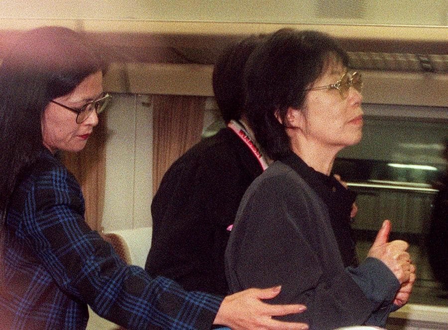 Fusako Shigenobu (centro), fondatrice dell’Armata Rossa giapponese, è scortata da agenti di polizia nella stazione di Tokyo l’8 novembre 2000 dopo essere stata arrestata a Osaka. (Photo by JIJI PRESS / AFP) / Japan OUT