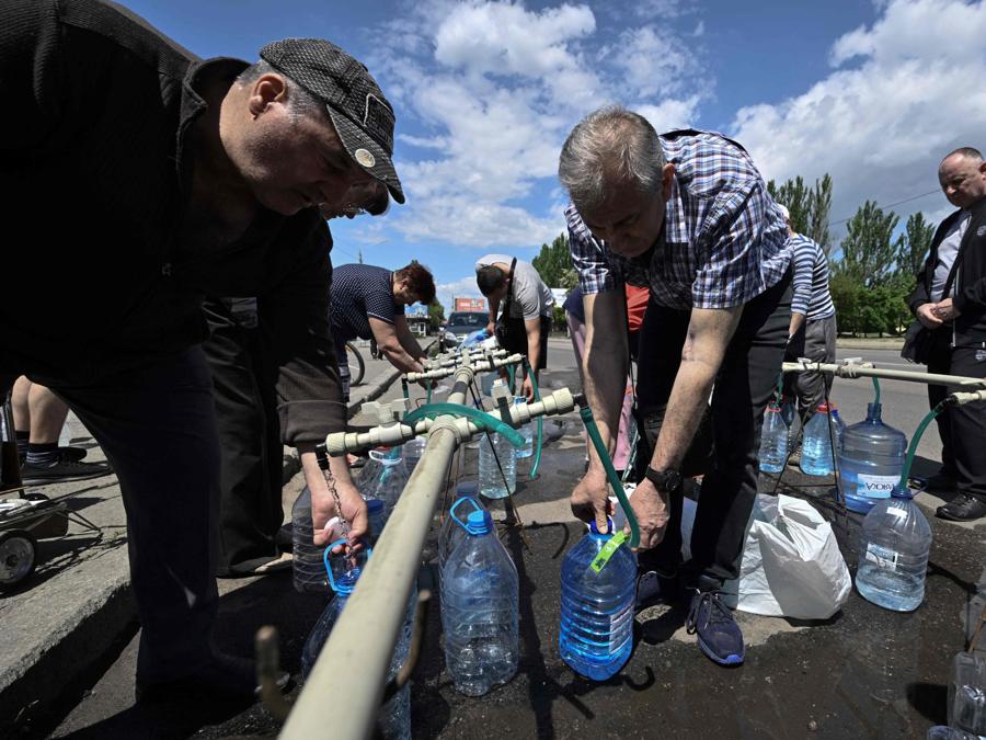 I residenti raccolgono acqua potabile da un camion di rifornimento nella città ucraina meridionale di Mykolaiv. (Photo by Genya SAVILOV / AFP)