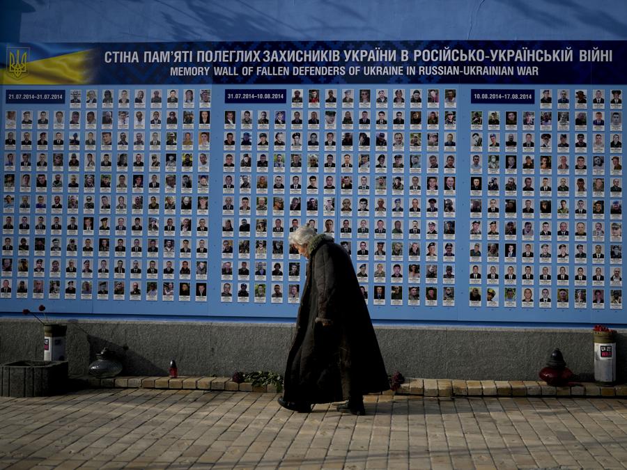 Una donna cammina davanti al muro commemorativo dei difensori caduti dell’Ucraina nella guerra russo-ucraina a Kiev. (AP Photo/Natacha Pisarenko)