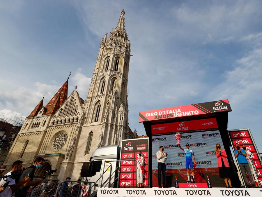 Simon Yates sul podio dopo aver vinto la tappa a cronometro individuale di 9.2 km. (Photo by Luca Bettini / AFP)