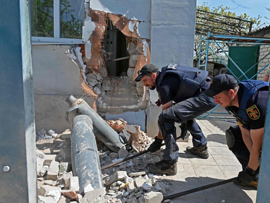 Esperti di esplosivi estraggono frammenti di missili russi da una casa, vicino alla città ucraina di Kharkiv. (Photo by SERGEY BOBOK / AFP)