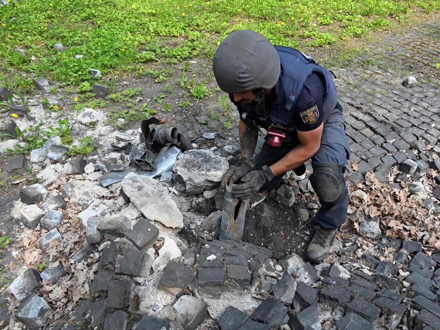 Un esperto di esplosivi estrae frammento di missile russo sul territorio del Memoriale alle vittime del totalitarismo alla periferia nord della città ucraina di Kharki. (Photo by SERGEY BOBOK / AFP)